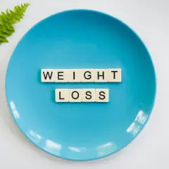 Niebieski talerz z literami "WEIGHT LOSS" i gałązką paproci. Idealny do planowania diety 10 kg w 2 tygodnie jadłospis.