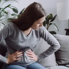 Kobieta z bólem brzucha, być może szukająca ulgi dzięki diecie FODMAP.