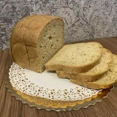 Chleb keto, pokrojony w kromki, prezentuje się apetycznie na złotym talerzyku z koronkową serwetką. Idealny na dietę ketogeniczną.