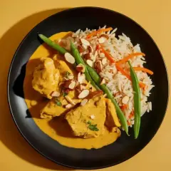 Pyszny kurczak curry w kremowym sosie, podany z ryżem, fasolką szparagową i migdałami.