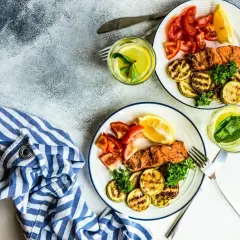 Dwa talerze z łososiem, grillowaną cukinią i pomidorami. Idealne danie na dieta low carb.