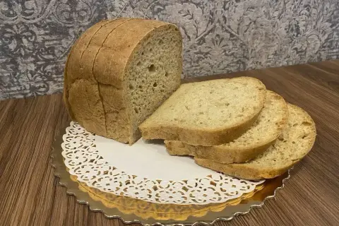 Chleb keto, pokrojony w kromki, prezentuje się apetycznie na złotym talerzyku z koronkową serwetką. Idealny na dietę ketogeniczną.
