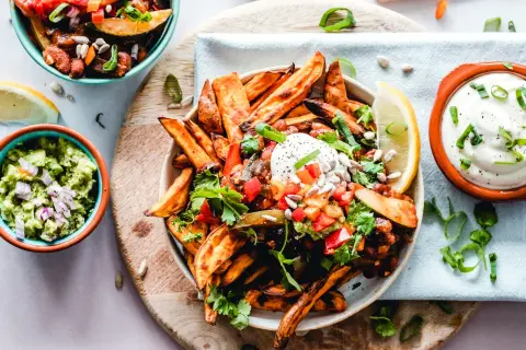 Kolorowe frytki z batatów z salsą, guacamole i śmietaną. Zdrowe jedzenie, które może pomóc w kontroli triglicerydów.