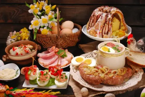 Bogaty stół na śniadanie wielkanocne: babka, biała kiełbasa, jajka faszerowane, chrzan, wędliny i żurek.