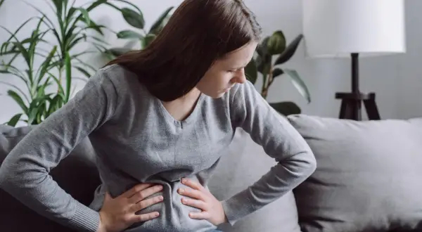 Kobieta z bólem brzucha, być może szukająca ulgi dzięki diecie FODMAP.