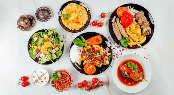 Mnóstwo pyszności na stole! Sałatka, hummus, pieczone warzywa, mięso i frytki – idealna zdrowa kolacja.