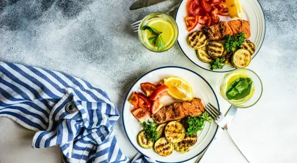 Dwa talerze z łososiem, grillowaną cukinią i pomidorami. Idealne danie na dieta low carb.