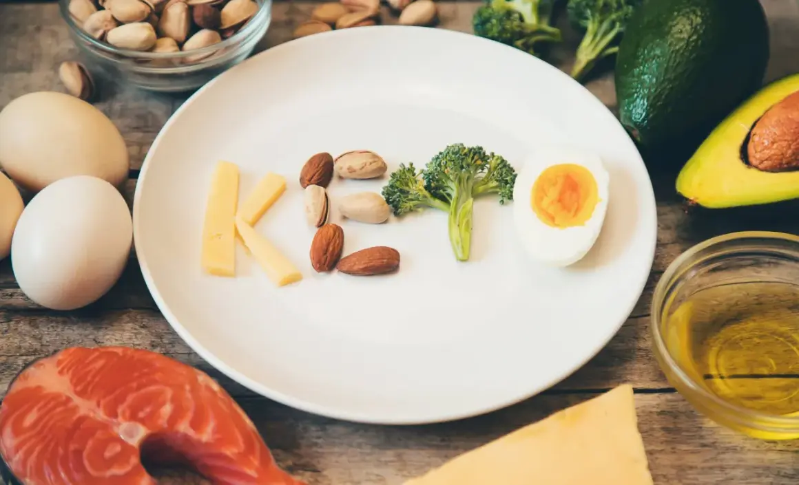 Litery KETO ułożone z sera, orzechów, brokuła i jajka. Czy dieta keto jest zdrowa? Obok łosoś, awokado, oliwa.