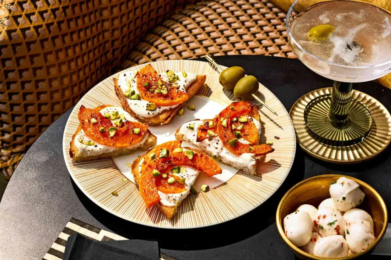 Lekka kolacja: tost z serkiem, pomarańczą i pistacjami. Obok oliwki, mini mozzarelle i drink.