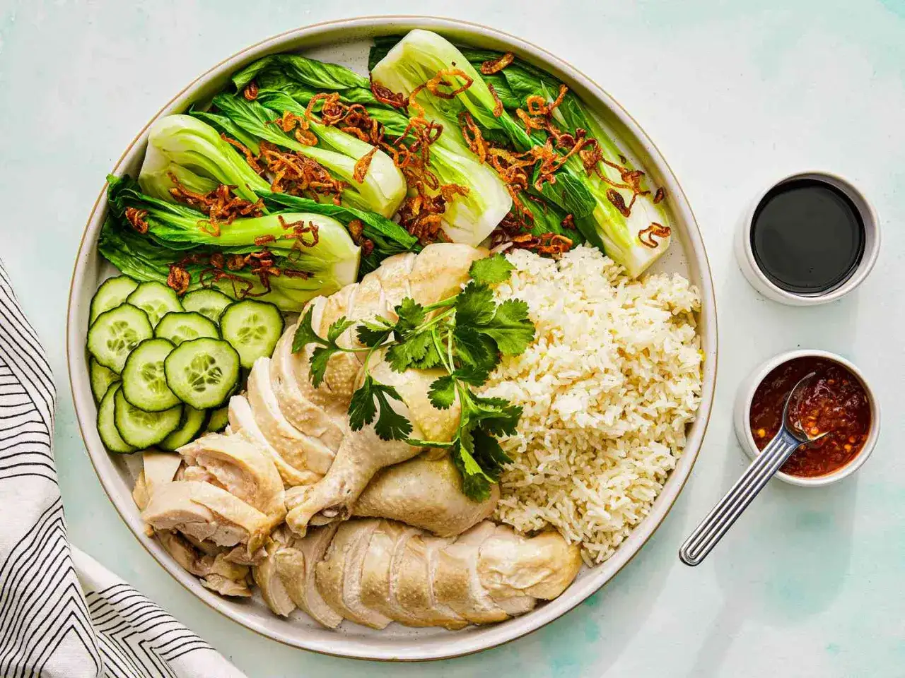 Pyszny kurczak w pięciu smakach z ryżem, chrupiącym bok choy, ogórkiem i sosami.