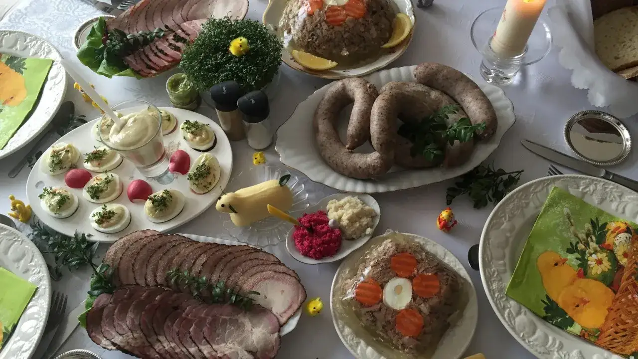 Obfite śniadanie wielkanocne: wędliny, kiełbasy, jajka faszerowane, galareta, chrzan, masło w kształcie baranka i dekoracje.