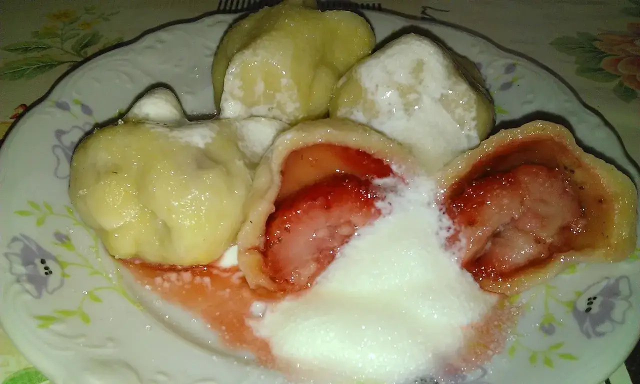 Pierogi z truskawkami, przepis babci. Pyszne, domowe pierożki z soczystymi truskawkami, polane śmietaną i posypane cukrem.