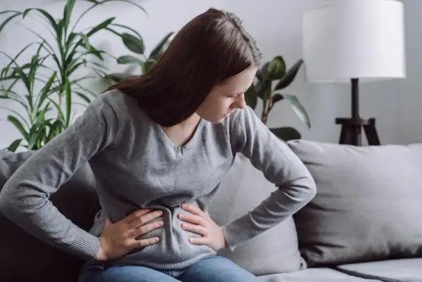 Kobieta z bólem brzucha, być może szukająca ulgi dzięki diecie FODMAP.