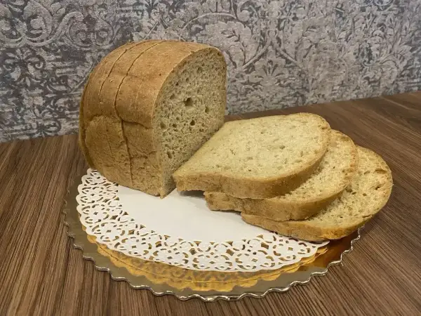 Chleb keto, pokrojony w kromki, prezentuje się apetycznie na złotym talerzyku z koronkową serwetką. Idealny na dietę ketogeniczną.