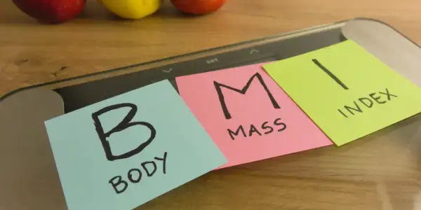 Na wadze leżą karteczki z napisem "BODY MASS INDEX". Dążenie do prawidłowego BMI to klucz do zdrowia.