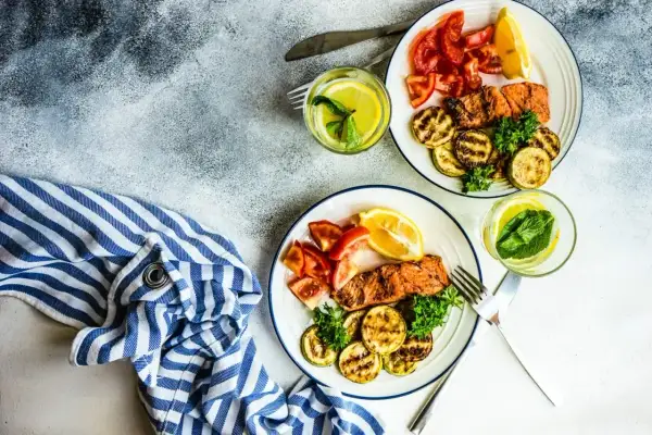 Dwa talerze z łososiem, grillowaną cukinią i pomidorami. Idealne danie na dieta low carb.